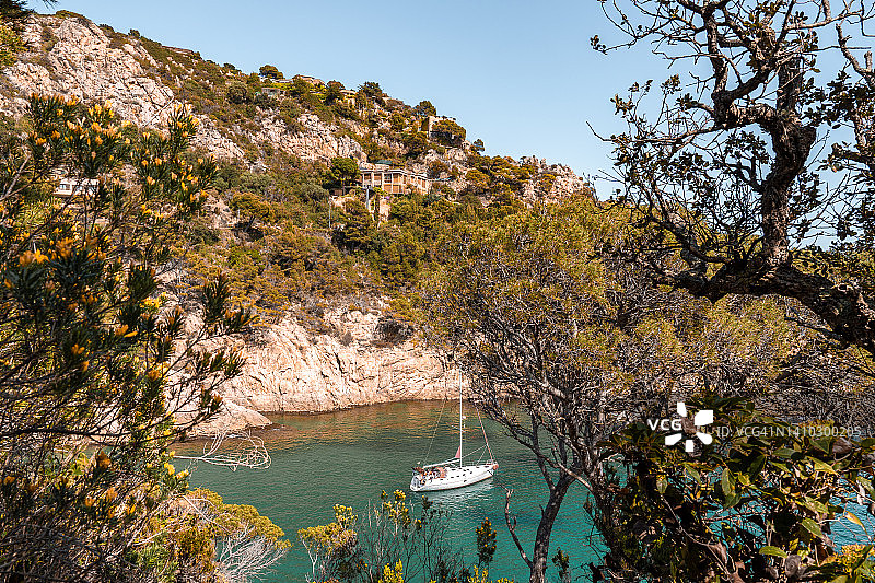 有岩石山和树木的沿海景观。在西班牙布拉瓦海岸航行的小船或游艇图片素材