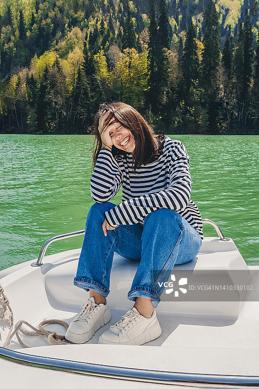 快乐的年轻女子双手抱头坐在丽察湖的船上图片素材