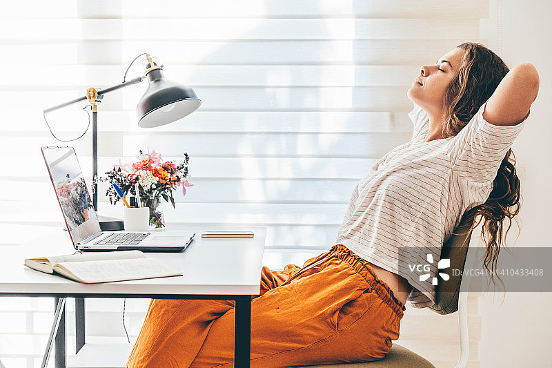 女性在家使用笔记本电脑工作时休息。图片素材