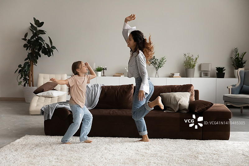 快乐的女人带着她的小女儿在客厅跳舞图片素材