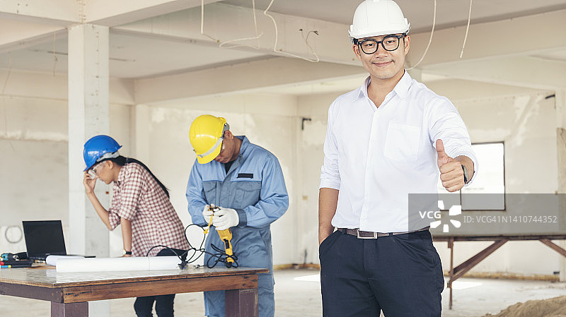 亚洲工程师男子头脑风暴建设建设承包商土木工人合作伙伴团队会议在施工现场。蓝图工程师安全帽工人安全帽放在桌子上。工程师团队合作咨询图片素材