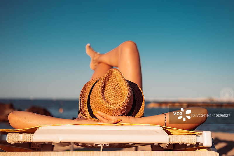 戴着草帽的女人在海滩上休息和放松。图片素材