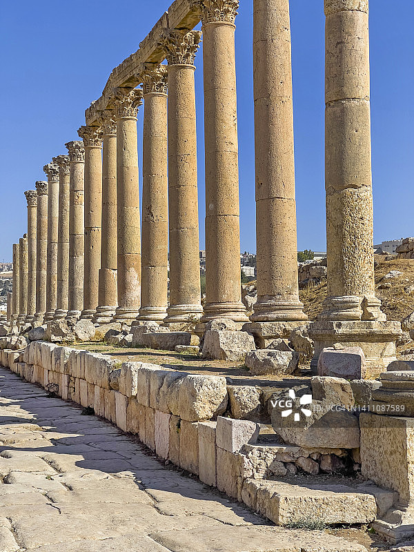 经典的科林斯式圆柱排列在杰拉什罗马遗址中心的石砌街道或车行道上。图片素材