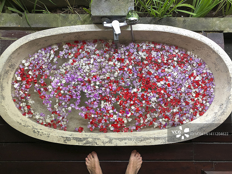 印度尼西亚巴厘岛，一名男子站在满是鲜花的浴缸前图片素材