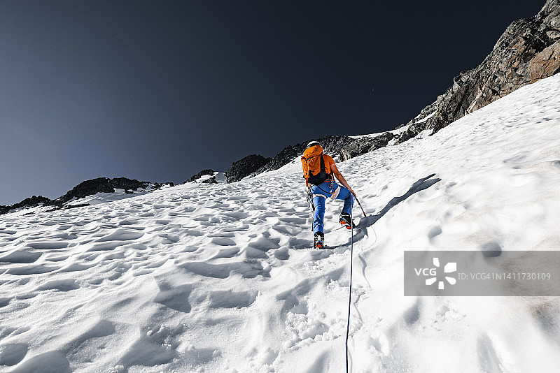在不列颠哥伦比亚省，一名男登山者正在攀登陡峭的积雪覆盖的山峰图片素材