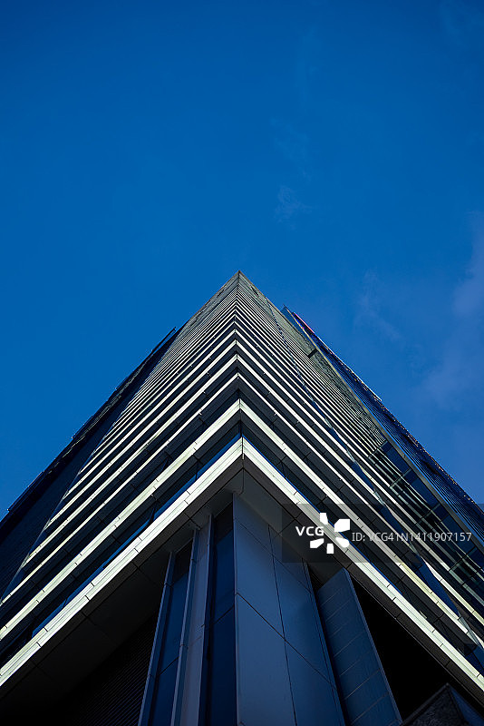 现代玻璃摩天大楼外立面对清澈的蓝天在晚上图片素材