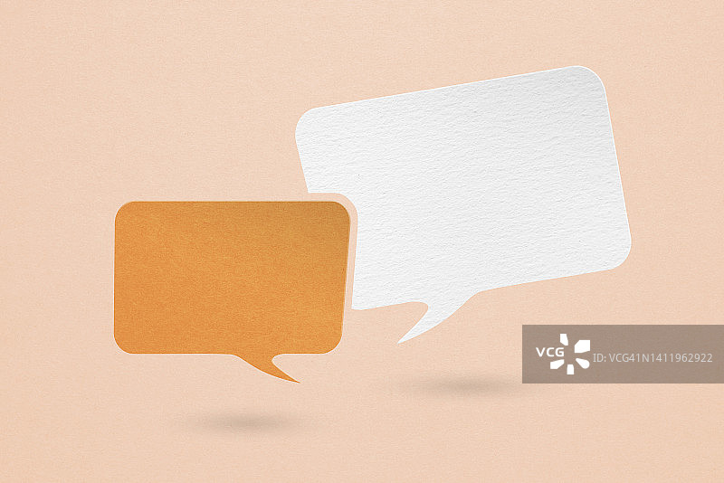 两个空白的白色和橙色的演讲泡沫纸剪纸，在垃圾橙色的纸背景。关于沟通和社交媒体的概念形象图片素材
