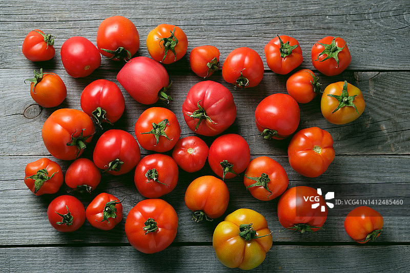 成熟的红黄番茄放在木桌上。素食，纯素食和生食。有机自制农产品。在花园里收割，在菜园，在乡下。食品的背景。道德消费。从农场到餐桌。图片素材