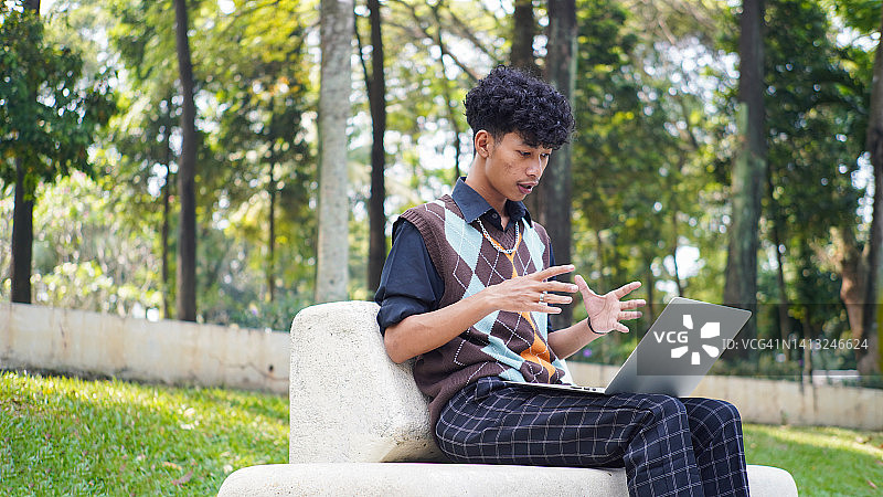 亚洲少年在公园里使用笔记本电脑图片素材