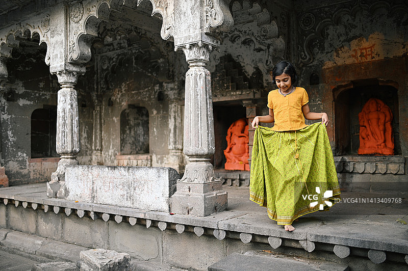 可爱的女孩穿着印度传统服装走在寺庙里。图片素材