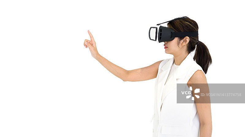 亚洲白衣女子使用虚拟现实眼镜，玩互动游戏。侧视图。未来科技的概念。图片素材