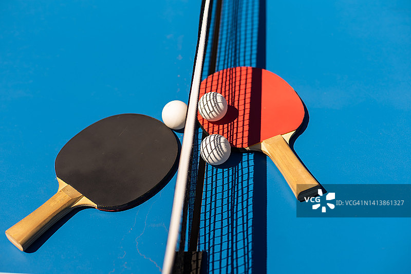 乒乓球拍和蓝色背景的白色塑料球。图片素材
