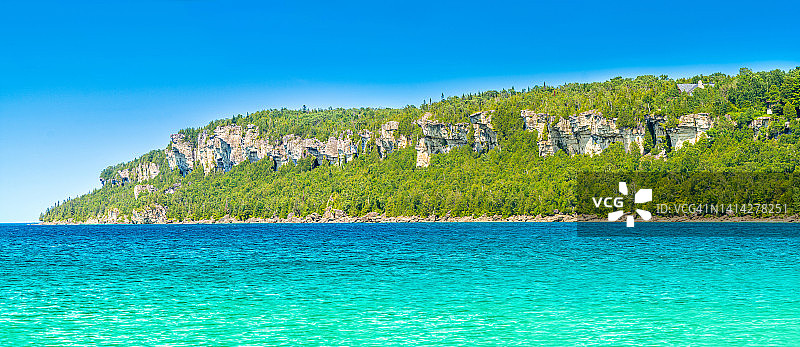 惊人的清洁的淡水和绿色云杉森林在狮子头海滩港口的岩石在加拿大安大略省狮子头省级公园。休伦湖地峡湾。是个度假旅游的好地方。图片素材