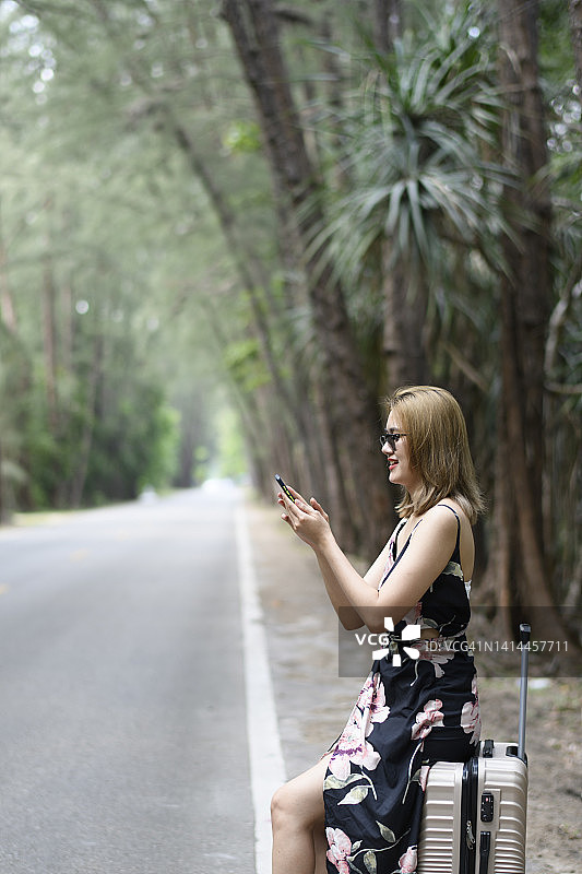 一名女子在路上用智能手机叫出租车图片素材