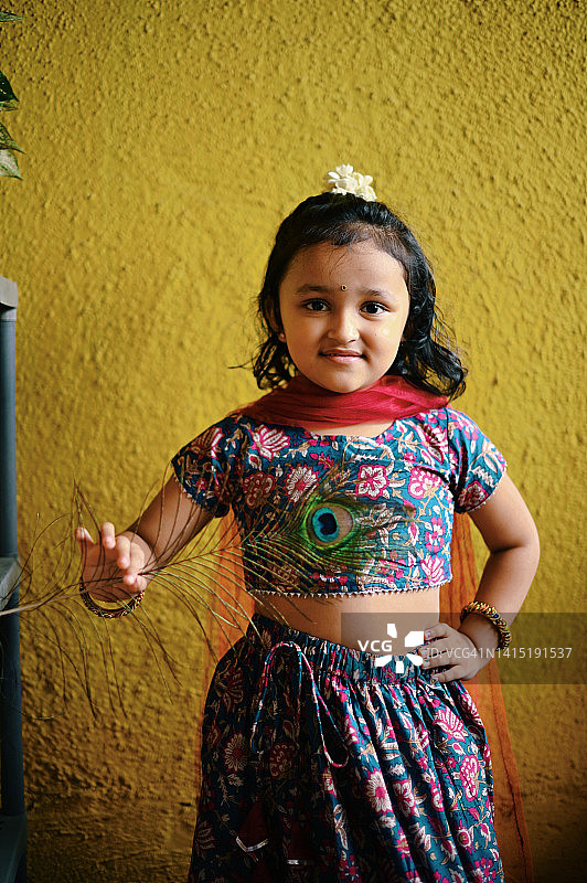 穿着印度传统服装的可爱女孩手持孔雀羽毛的肖像图片素材