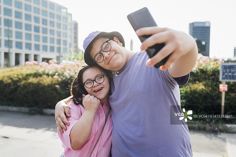 微笑的哥哥在阳光明媚的日子里用手机和妹妹自拍图片素材