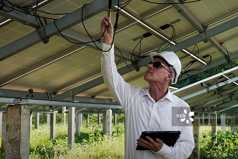 太阳能农场(太阳能板)的工程师使用平板电脑检查系统的操作。世界节能光伏组件概念清洁能源发电图片素材