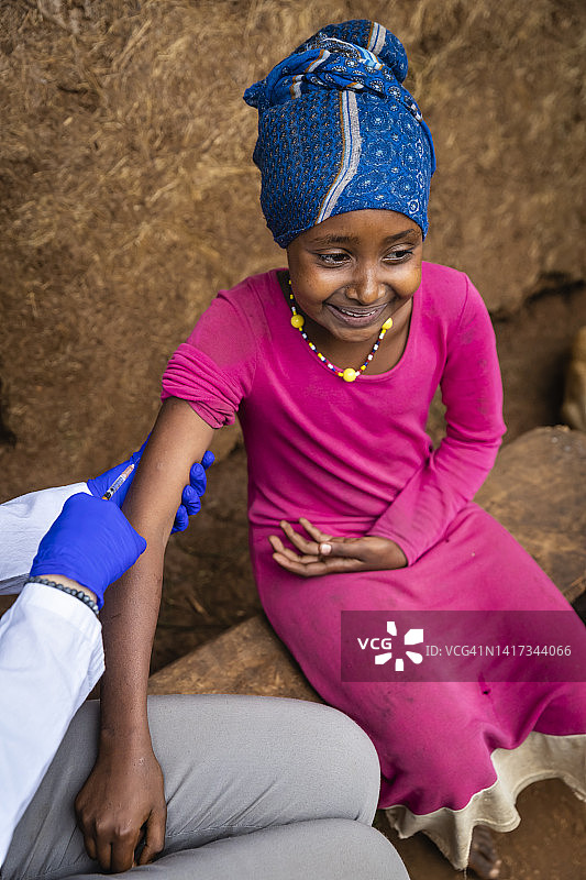在东非的一个小村庄，一名女医生正在给一名年轻的非洲女孩打针图片素材