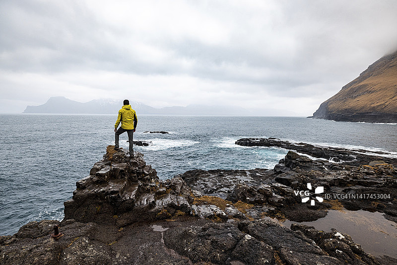 法罗群岛，Eysturoy, Gjogv，一名男性徒步旅行者在悬崖边欣赏大西洋图片素材