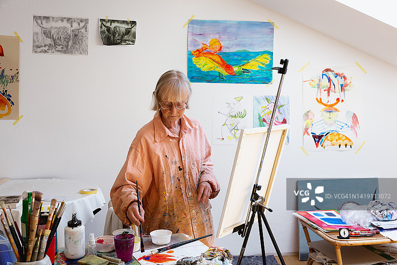 一位艺术家的肖像:一位年长的女性在她的工作室绘画图片素材