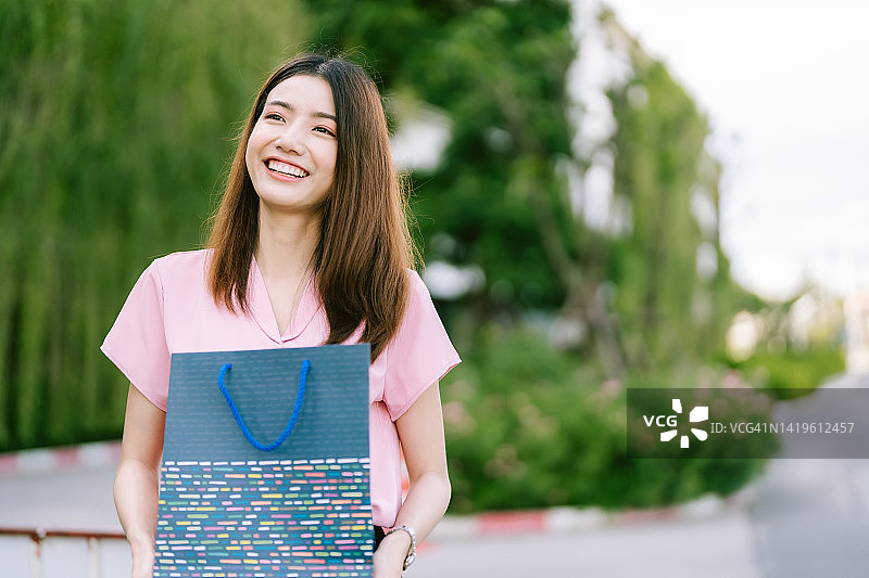 亚洲妇女高兴地拿着购物袋在城市购物中心。图片素材