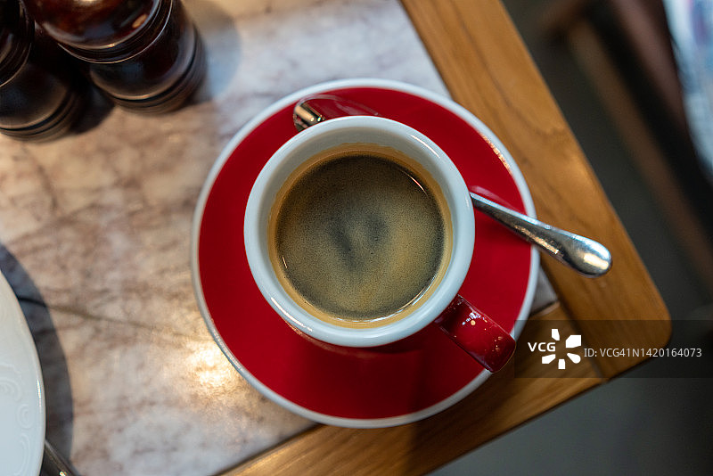 黑咖啡放在正上方的红色杯子里。带咖啡因的热咖啡，特写。餐厅餐桌上的早餐新鲜饮料。高角度视角，水平图片素材