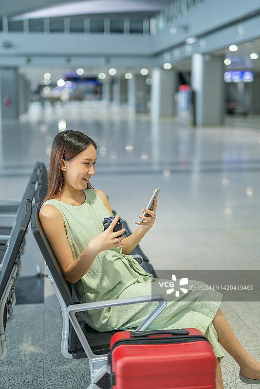 一个年轻的亚洲女性的肖像照片与她的手机和行李箱准备和去她的梦想的度假目的地旅行图片素材
