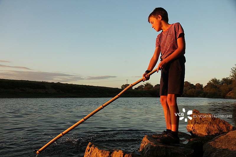 日落时分，小男孩在河边图片素材