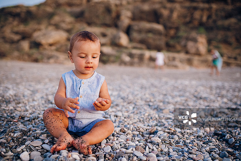 婴儿在沙滩上玩鹅卵石图片素材