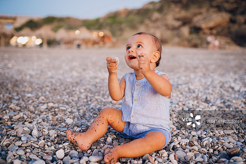 婴儿在沙滩上玩鹅卵石图片素材