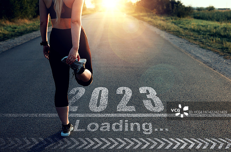 运动女孩谁是在起跑线通过2023年和装载酒吧画在沥青。新概念的专业成就在新的2023年和成功。图片素材