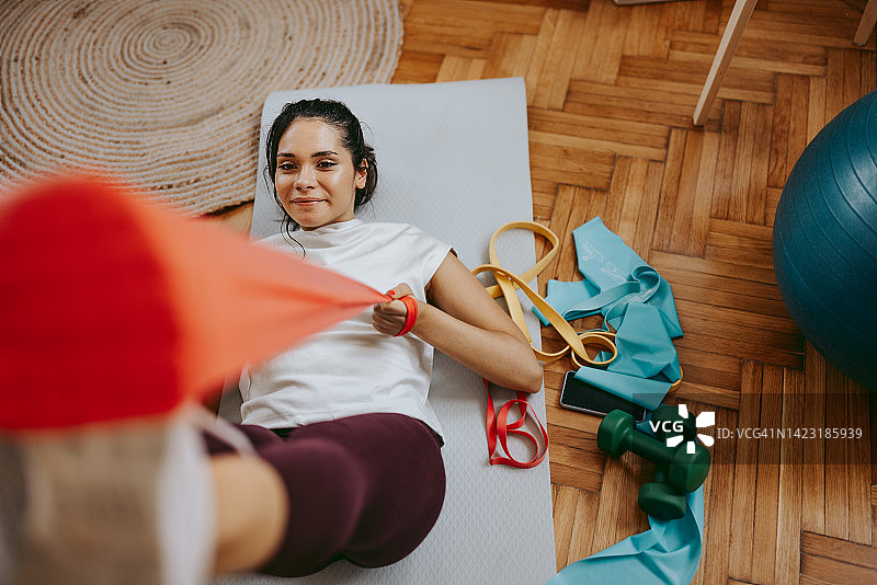 运动妇女做健身训练在家里与阻力带图片素材