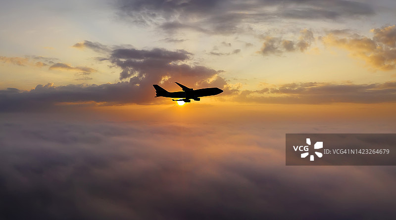 日落时分的飞机在云层之上。乘飞机旅行图片素材