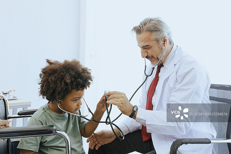 医生在体检室内用听诊器给小男孩病人把脉，以达到保健和医药行业的理念。图片素材