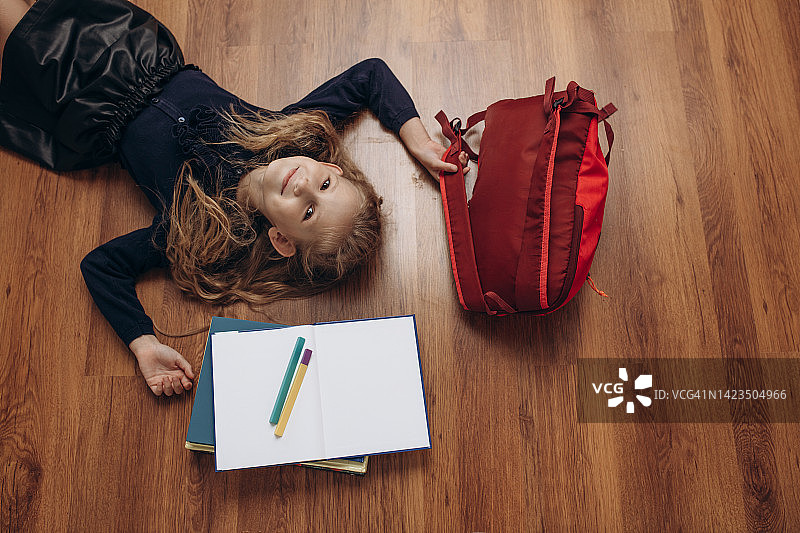 漂亮的小女孩-女学生带着书，笔记本，钢笔和背包，肖像在地上，俯视图图片素材