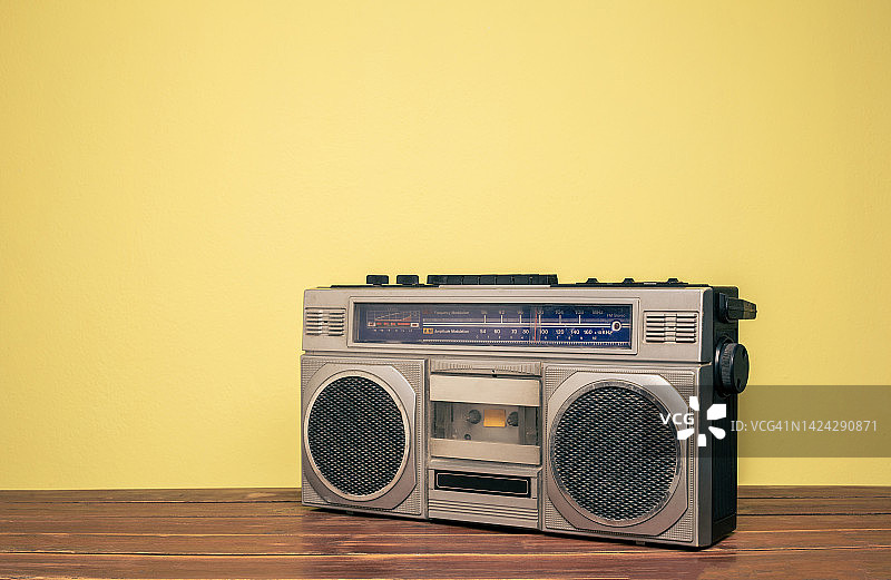 复古便携式立体声录音机在木制桌子上的黄色背景。图片素材