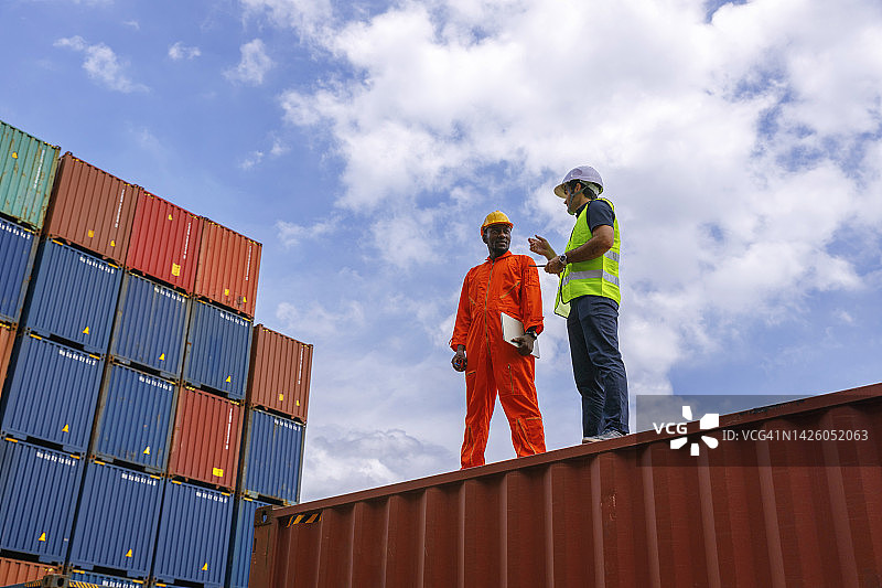 工头带领工人在集装箱仓库进行货物物流、进出口运输或货物运输的质量控制。图片素材