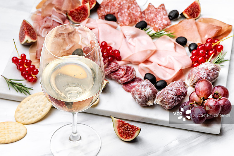 两杯白葡萄酒或普洛塞克配开胃菜意大利腊肠火腿橄榄浆果。开胃食品图片素材