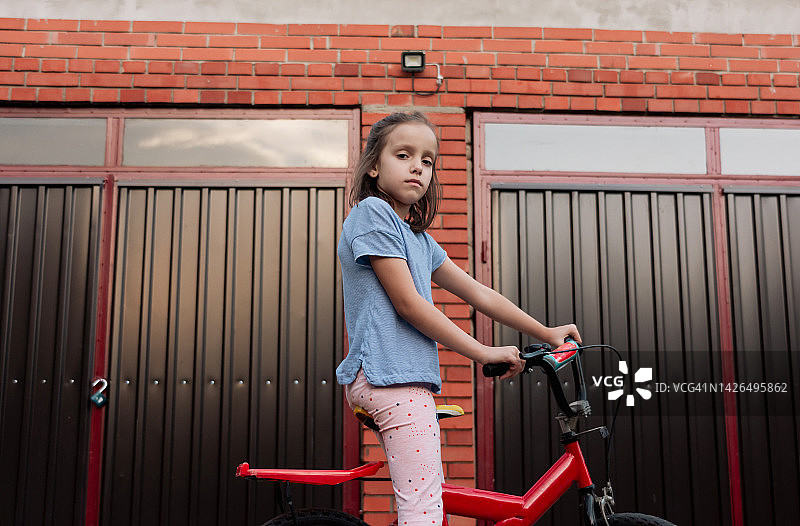 一个骑着自行车的女孩站在院子里的画像图片素材