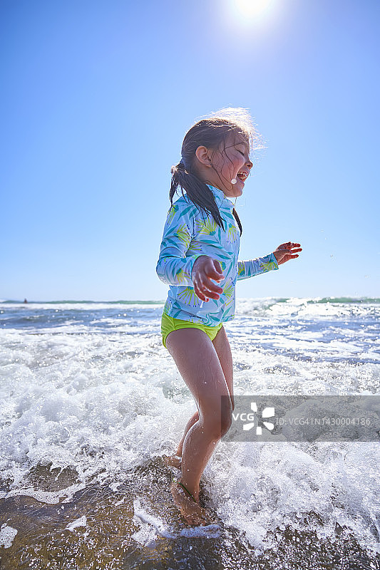 一个女孩在波涛汹涌的海面上玩耍。图片素材