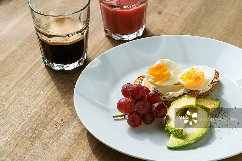 早餐有煮鸡蛋，牛油果，葡萄，一杯新鲜咖啡和水果冰沙图片素材