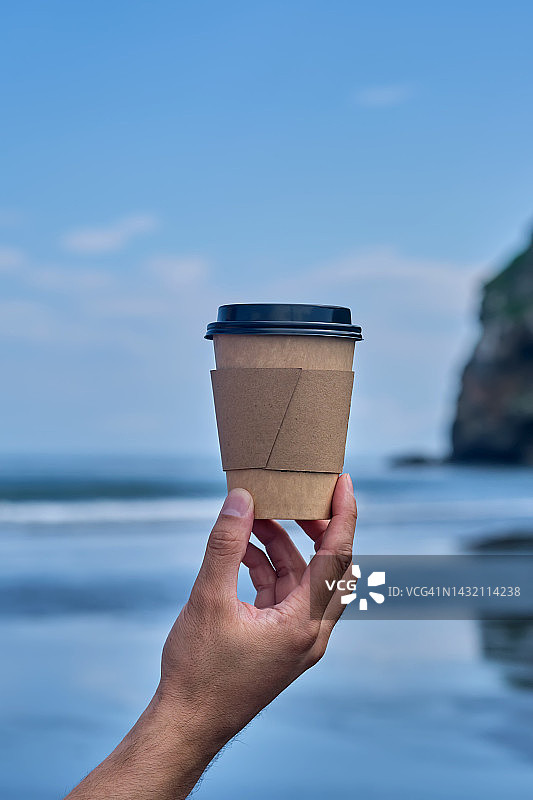 一杯以自然、海洋和山脉为背景的咖啡。图片素材