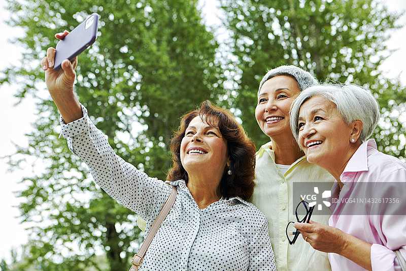 三个成熟的女人在户外玩现代智能手机的新移动应用图片素材