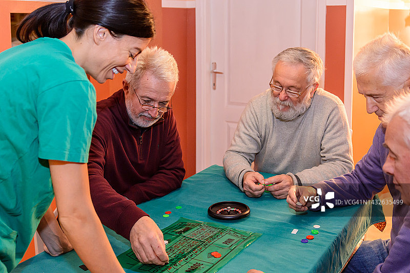 社交聚会上的老年人正在桌子上玩轮盘赌，玩得很开心。图片素材