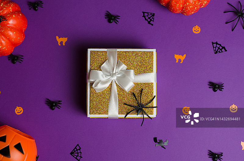 万圣节礼物和大甩卖。金色礼盒和传统的万圣节装饰在紫色的背景图片素材