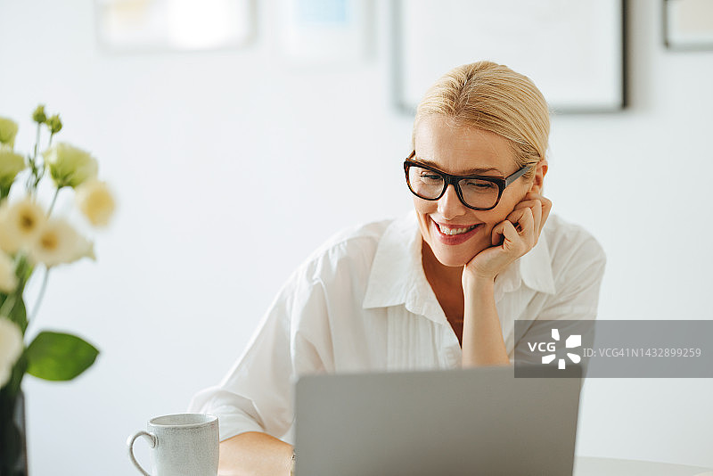 微笑的商务女性在工作中使用笔记本电脑图片素材