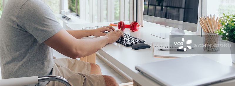 穿着t恤的休闲男性在家里用电脑打字打字图片素材