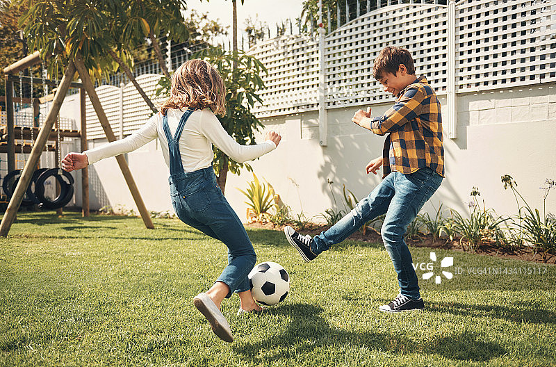 玩耍、游戏和孩子们在花园里进行足球训练，一起在自己家里锻炼健身。年轻，快乐和运动的女孩，男孩或朋友在他们家的后院踢足球图片素材