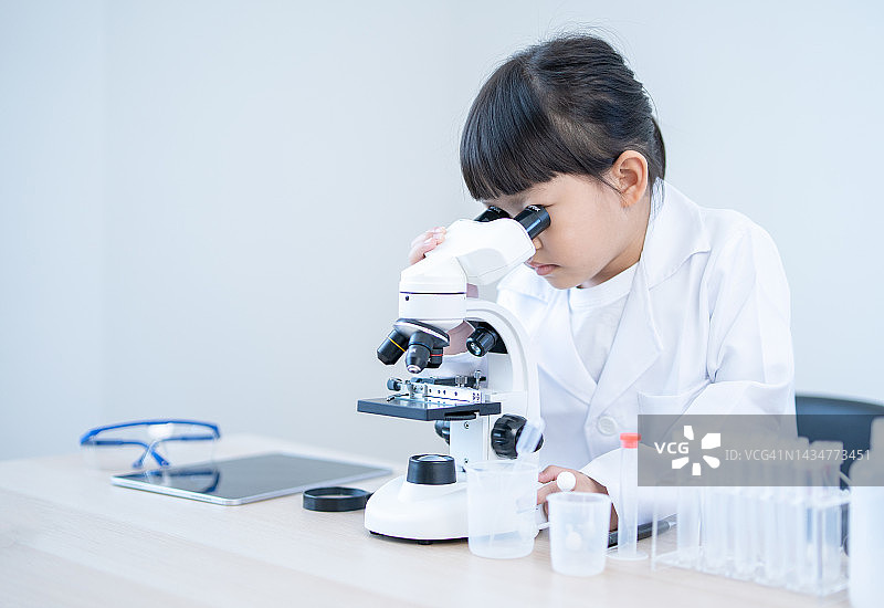 亚洲女孩在学校科教实验室学习和使用显微镜图片素材