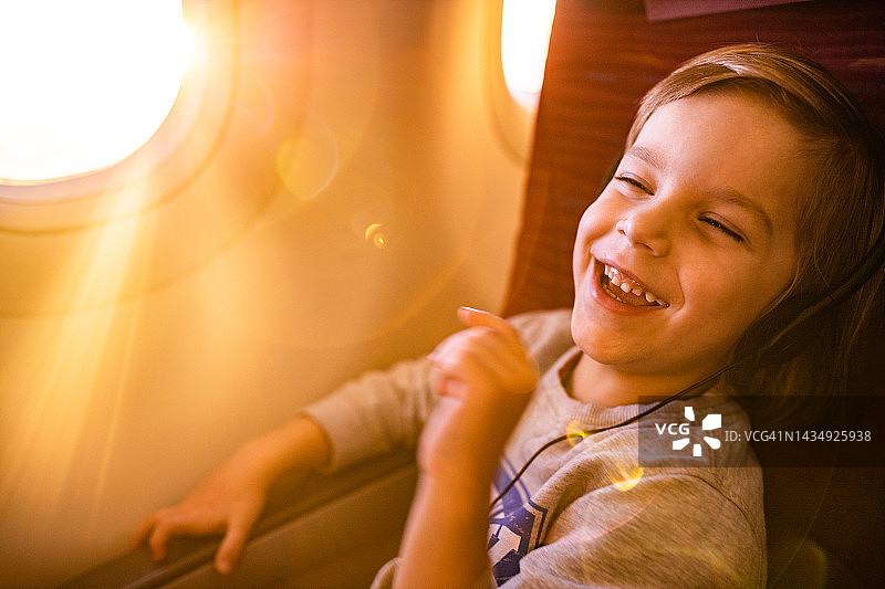 快乐的男孩在飞机上享受着音乐。图片素材